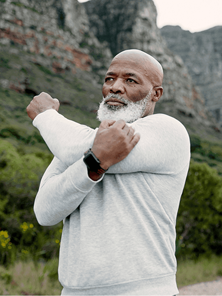A man stretching his shoulder in nature